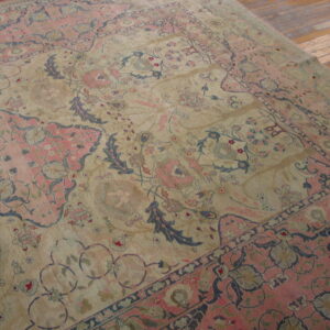 Faded beige and rose traditional rug with dark blue floral accents rests on rustic wood floors.