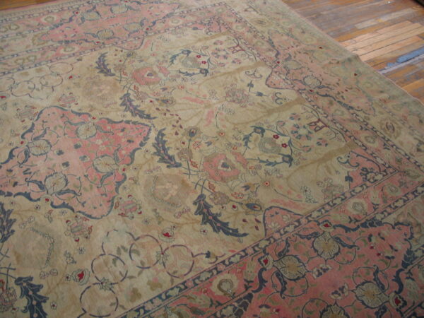 Faded beige and rose traditional rug with dark blue floral accents rests on rustic wood floors.
