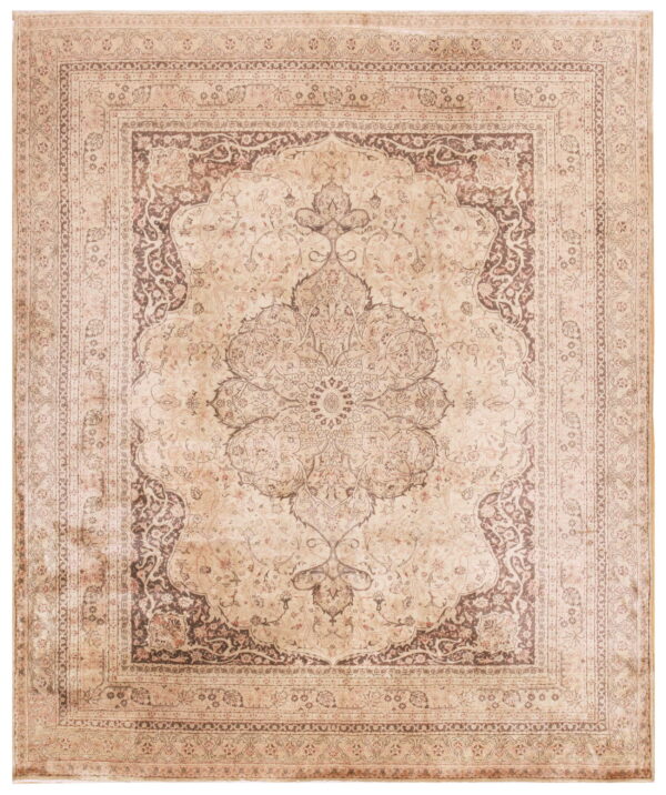 Traditional low pile rug in muted tan and brown with an ornate central medallion and complex borders.