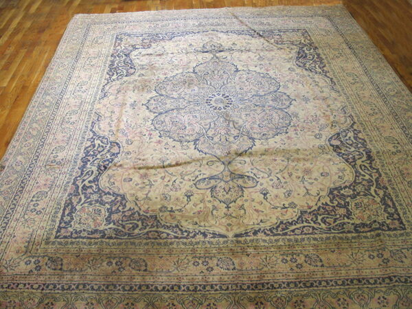 Beige rug with a large navy floral medallion and rose accents on polished wood floor.