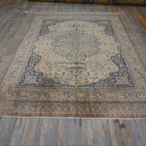 Low-pile traditional rug in beige, navy, and pale pink colors on distressed wood flooring.