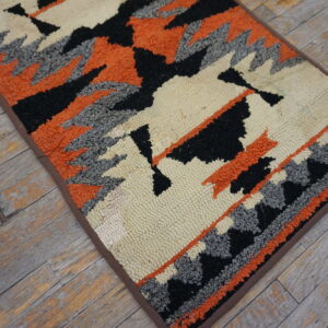 Loop-textured rug runner with black, orange, gray, and cream geometric patterns on distressed wood.