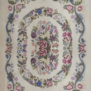 Off-white rug featuring a dense, muted floral medallion of pink, blue, and purple blossoms.