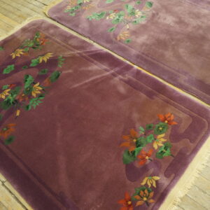 Two plum rugs with carved orange and green floral motifs lay on light wooden plank flooring.