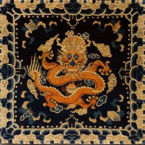 Dark blue rug with a central orange dragon and beige border motifs, placed on rustic wooden plank flooring.