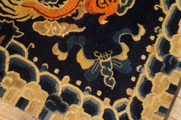 Close-up of a textured high-pile rug in gold, orange, and blue with ornate stylized motifs.