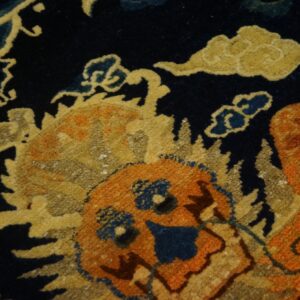 Close-up shows a navy blue rug pattern featuring orange and yellow figures surrounded by stylized blue and gold clouds.