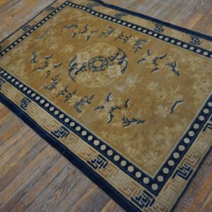Gold rug with a central medallion, blue borders, and floral motifs rests on distressed wood plank flooring.