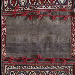 A long vertical textile featuring two geometric red, blue, and cream panels separated by a plain dark gray center.