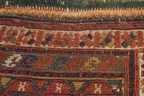 Detailed view of a flat-woven rug border showing intricate geometric patterns in red, blue, teal, and gold.
