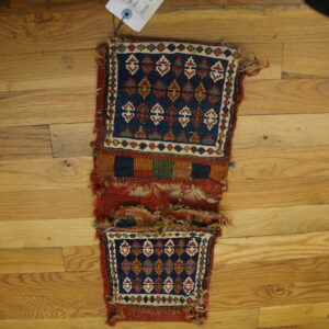Two connected blue and red geometric flatweave panels separated by a striped band on wooden floorboards.