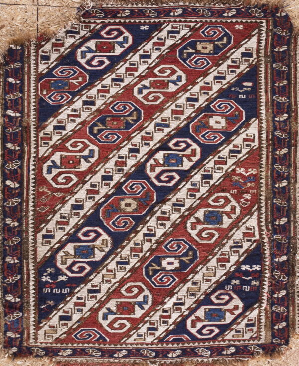 Flatwoven rug featuring diagonal stripes in red, navy blue, and cream with complex geometric motifs.