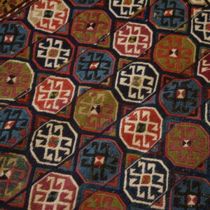 A dense geometric rug pattern features multicolored octagonal medallions in navy, teal, red, and olive green.