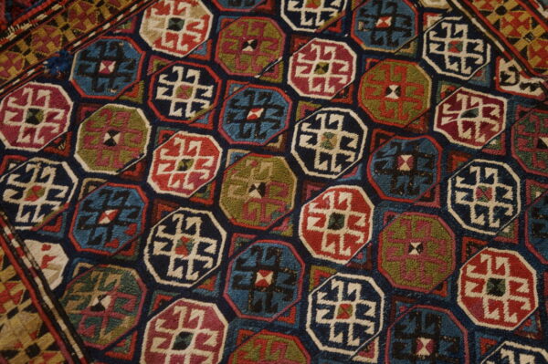 A dense geometric rug pattern features multicolored octagonal medallions in navy, teal, red, and olive green.