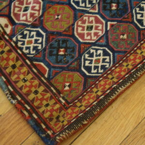 Blue, red, and green octagonal medallions fill this low-pile rug with a geometric border on light hardwood flooring.