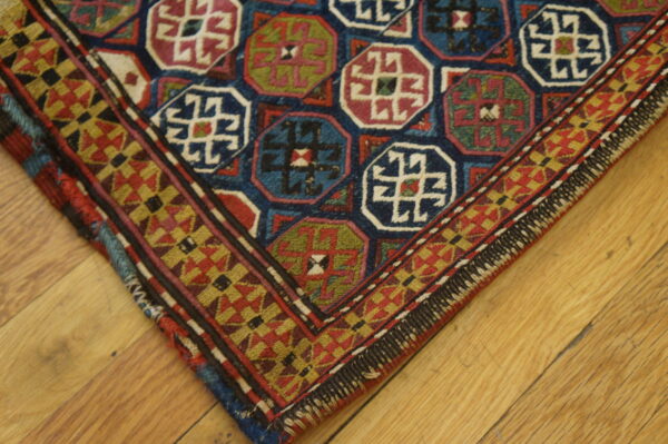 Blue, red, and green octagonal medallions fill this low-pile rug with a geometric border on light hardwood flooring.