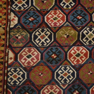 Low-pile rug displaying colorful octagonal motifs and geometric borders on light wood flooring.