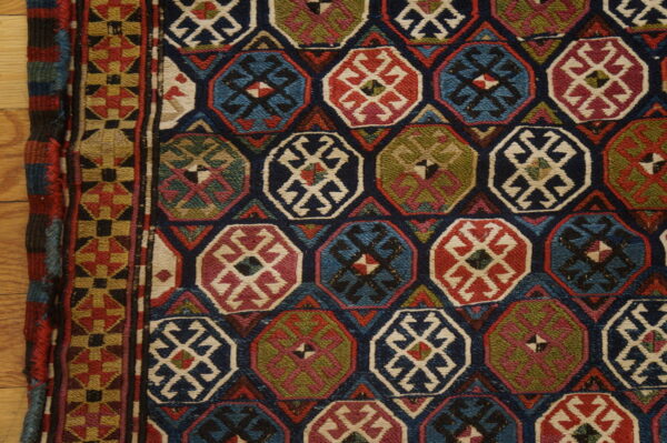 Low-pile rug displaying colorful octagonal motifs and geometric borders on light wood flooring.