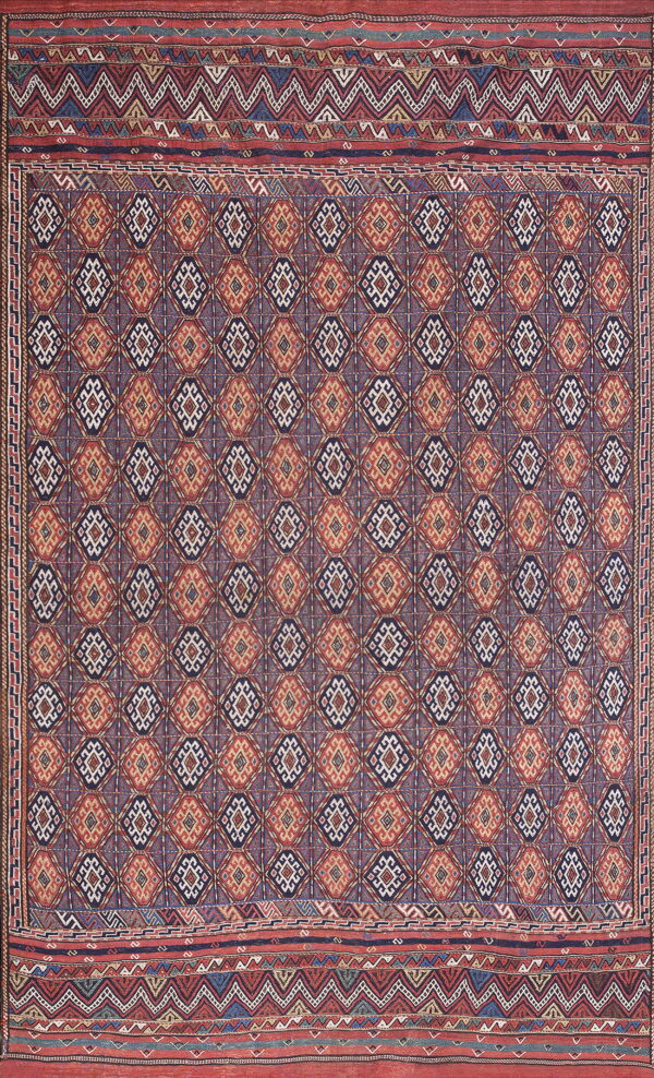 Intricate low-pile rug featuring red, dark blue, and cream geometric diamond patterns with wide zigzag borders.