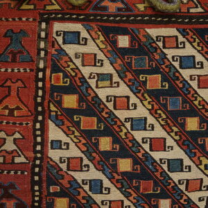 Detailed view of a flatweave rug with a red border and a field of navy and beige diagonal geometric stripes.