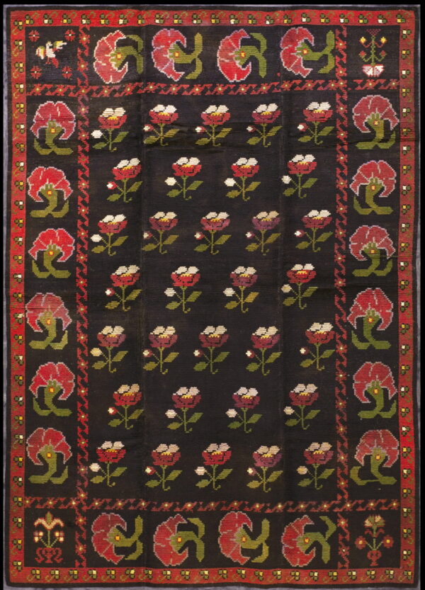 Black rug with a repeating pattern of red and white stemmed flowers and a broad red floral border.