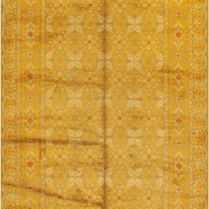 A rectangular, high-pile rug in golden yellow with repeating faded floral and geometric border patterns.