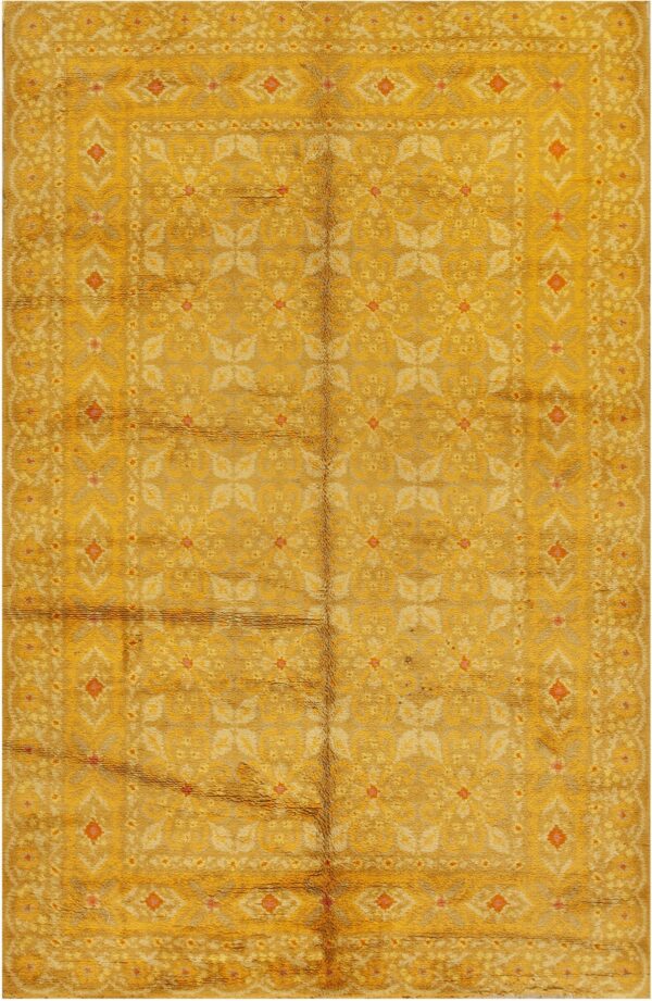 A rectangular, high-pile rug in golden yellow with repeating faded floral and geometric border patterns.