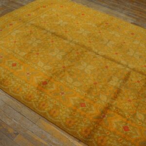 Mustard yellow high-pile rug featuring a patterned field with bright orange accents on rustic wood floors.