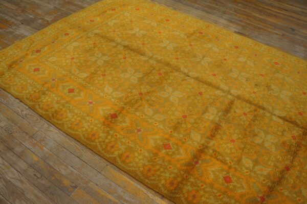 Mustard yellow high-pile rug featuring a patterned field with bright orange accents on rustic wood floors.