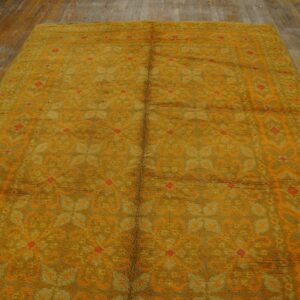 High-pile shag rug in mustard yellow and orange geometric patterns sits on rustic wood plank flooring.