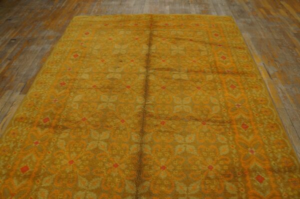 High-pile shag rug in mustard yellow and orange geometric patterns sits on rustic wood plank flooring.