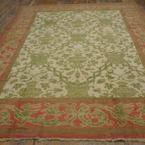 Ornate green and coral patterned rug with a light field, displayed on rustic wood plank flooring.