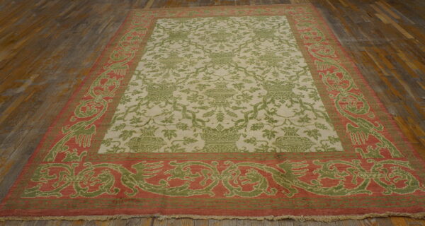 Ornate green and coral patterned rug with a light field, displayed on rustic wood plank flooring.