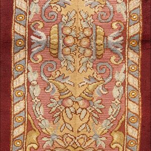 Ornate red runner rug with a central panel of low-pile gold, pink, and blue scrolling floral and fruit designs.