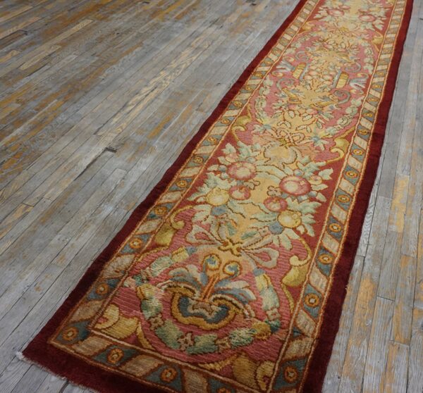 Ornate floral runner in rose, yellow, and sage green rests on rustic gray-toned wood planks.