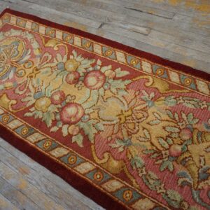 Traditional floral runner in rose, gold, and blue with a deep red border on weathered plank flooring.