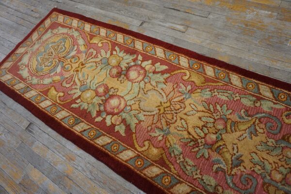 Traditional floral runner in rose, gold, and blue with a deep red border on weathered plank flooring.