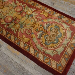 A plush runner with a maroon, yellow, and blue ornate floral pattern lies on distressed gray wood flooring.