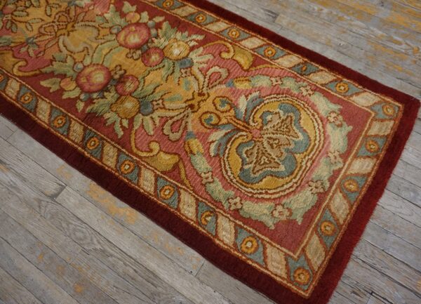 A plush runner with a maroon, yellow, and blue ornate floral pattern lies on distressed gray wood flooring.