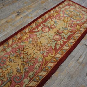 Low-pile runner with a traditional floral pattern in rose, gold, and blue on rustic gray wood planks.