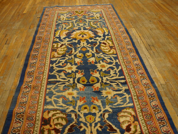 Traditional blue runner rug featuring intricate gold, cream, and red patterns on distressed wood planks.