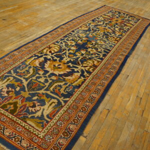 Traditional blue runner with intricate beige and terracotta patterns displayed on uneven wood plank flooring.