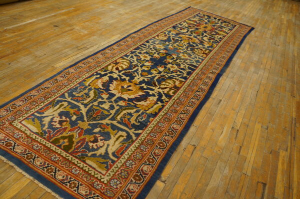 Traditional blue runner with intricate beige and terracotta patterns displayed on uneven wood plank flooring.