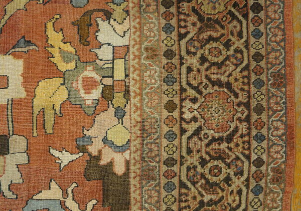 Rust, brown, beige, and blue rug detail showing an abstract field and complex patterned borders.