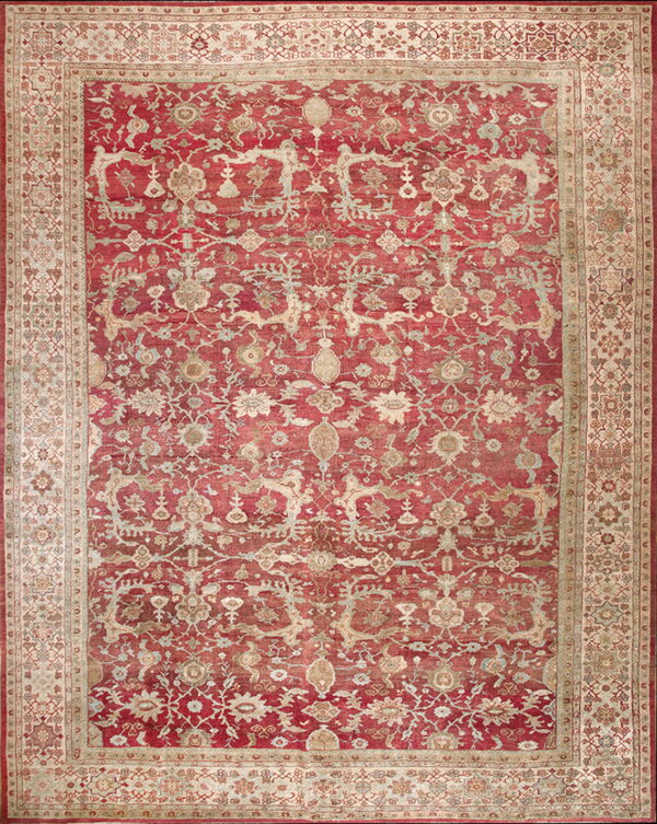 Full view of a red rug featuring distressed ornate floral and vine motifs with a wide beige border.