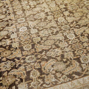 Distressed rug featuring a dense traditional pattern in earthy dark brown, tan, and faded cream colors.