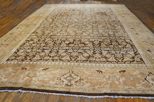 Low-pile rug with a dark brown field, beige florals, and wide gold/tan decorative borders on wood.
