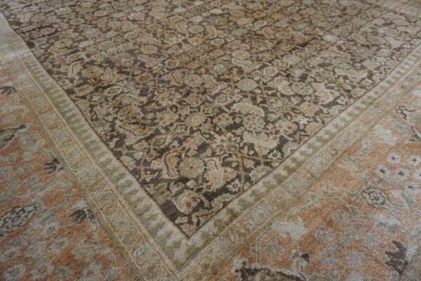 Muted traditional rug with a dense brown and beige floral pattern bordered by peach and olive bands.
