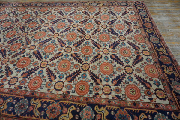 A large traditional rug with coral and navy botanical patterns on a cream field rests on distressed wood planks.