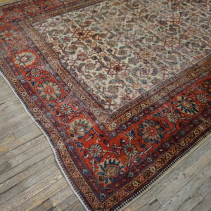 Traditional multicolor rug featuring an ivory field and red floral border on worn gray hardwood.